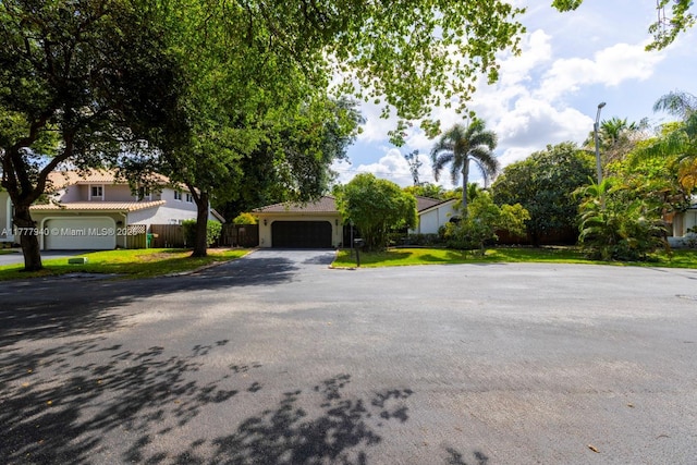 view of front of property with an attached garage, aphalt driveway, fence, and a front yard