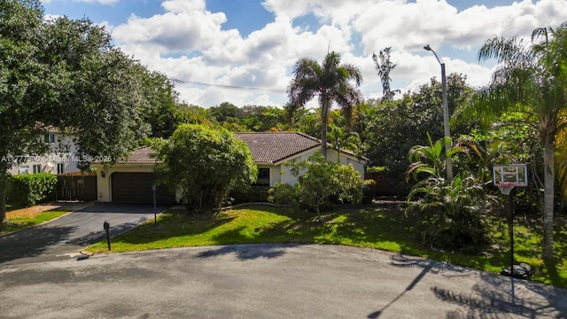 view of front of home with a tiled roof, driveway, a front yard, an attached garage, and stucco siding