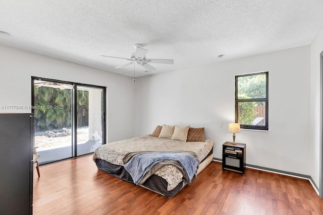 bedroom featuring access to outside, a textured ceiling, a ceiling fan, baseboards, and wood finished floors