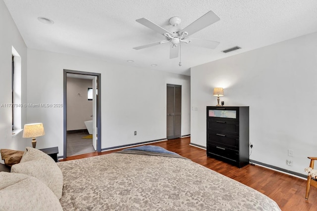 bedroom with a textured ceiling, baseboards, visible vents, and wood finished floors