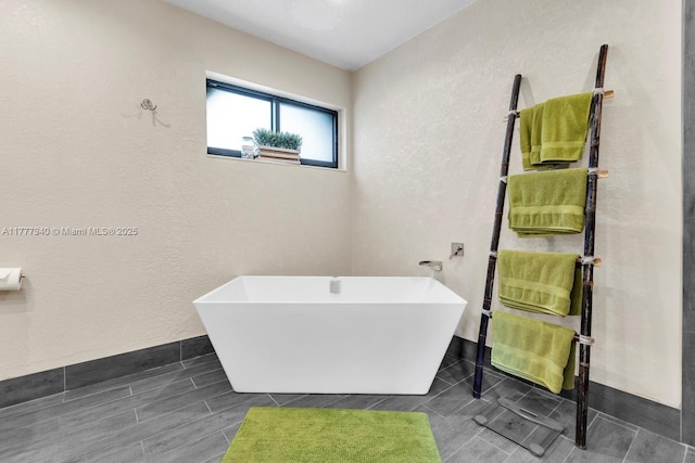 full bathroom featuring a textured wall and a freestanding bath