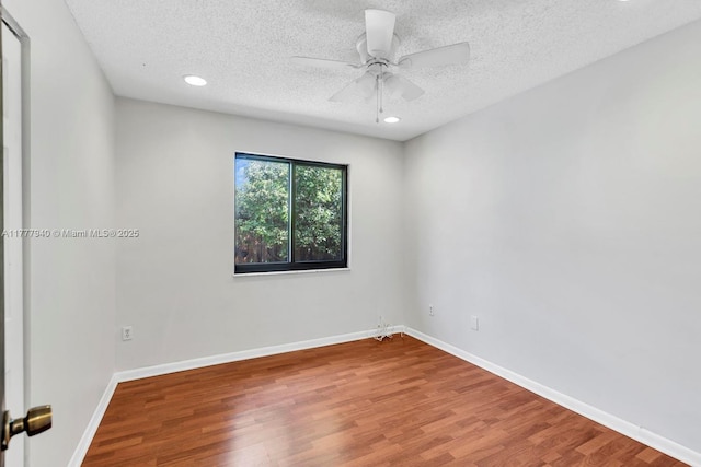 empty room with a textured ceiling, baseboards, recessed lighting, and wood finished floors