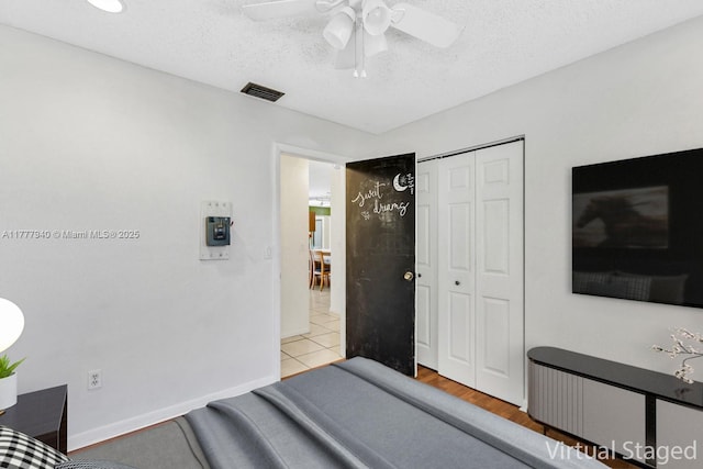 bedroom with visible vents, a closet, baseboards, ceiling fan, and a textured ceiling