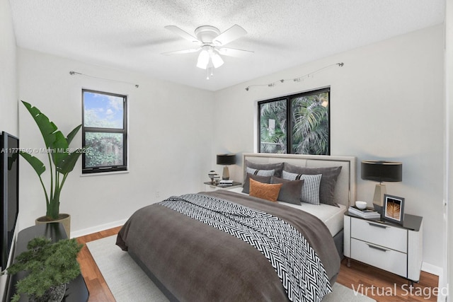 spare room with visible vents, wood finished floors, baseboards, ceiling fan, and a textured ceiling