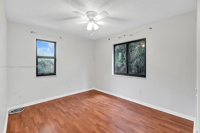 spare room with visible vents, wood finished floors, baseboards, ceiling fan, and a textured ceiling
