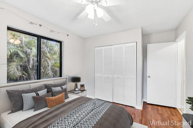 bedroom with a ceiling fan, a textured ceiling, wood finished floors, and a closet