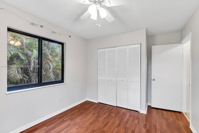 unfurnished bedroom featuring a textured ceiling, a ceiling fan, baseboards, wood finished floors, and a closet