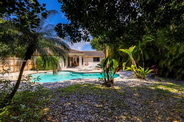 pool with fence, a ceiling fan, and a patio area