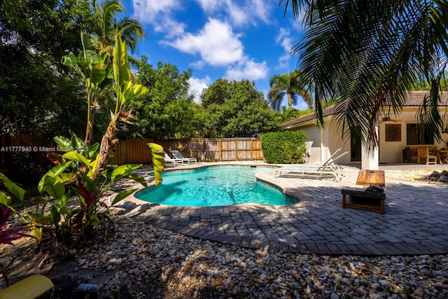 view of swimming pool featuring a fenced in pool, a fenced backyard, a fire pit, and a patio area