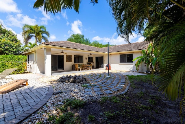 rear view of house with ceiling fan, stucco siding, and a tiled roof