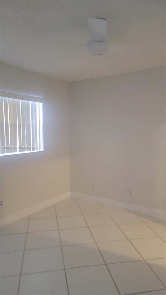 spare room with baseboards and tile patterned flooring