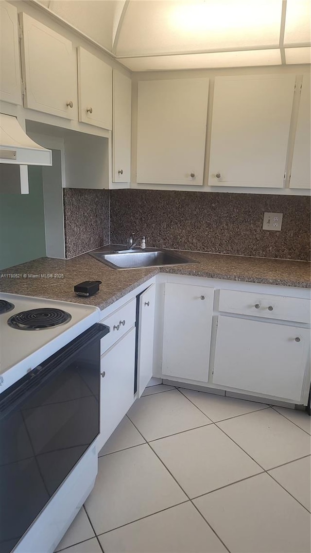 kitchen featuring light tile patterned floors, white electric stove, white cabinets, decorative backsplash, and a sink