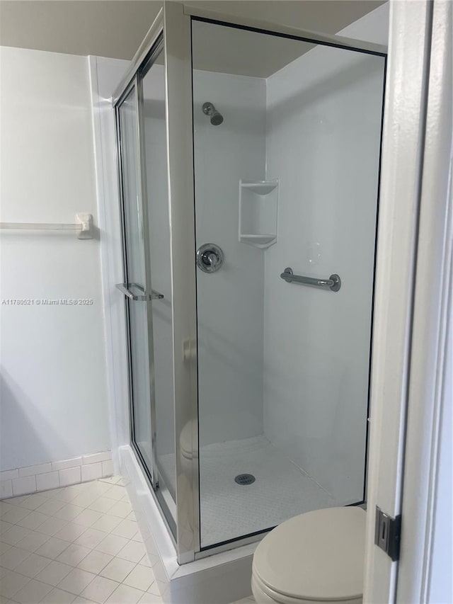 bathroom featuring a shower stall, tile patterned floors, and toilet