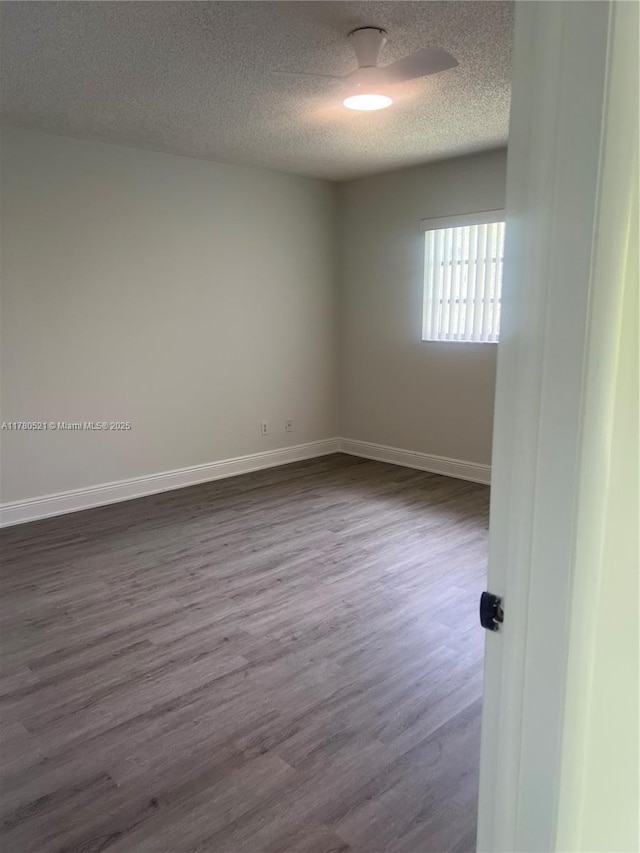 spare room featuring baseboards, a textured ceiling, and dark wood finished floors