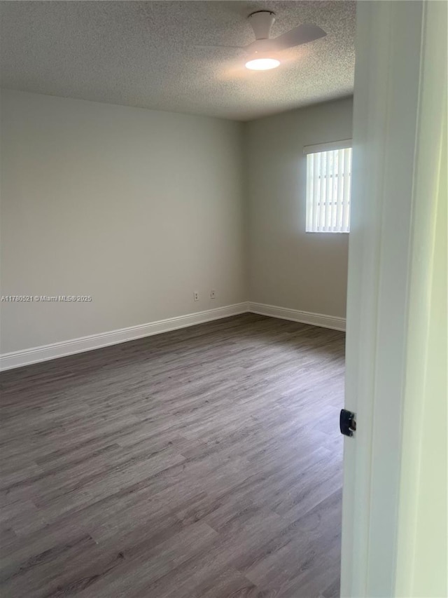 empty room with dark wood-style flooring, baseboards, and a textured ceiling