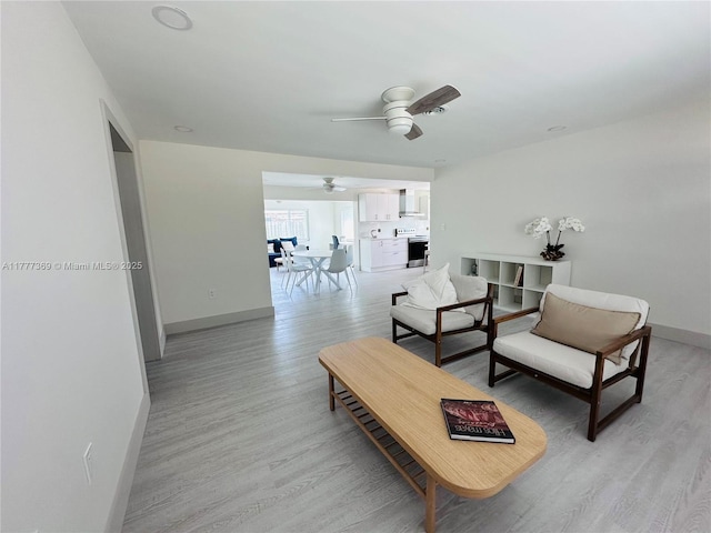 living room featuring light wood-style floors, a ceiling fan, and baseboards
