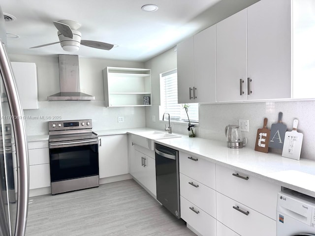 kitchen with wall chimney exhaust hood, stainless steel appliances, a sink, tasteful backsplash, and washer / clothes dryer