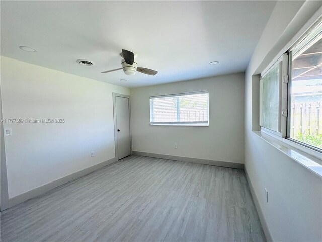 empty room with light wood finished floors, baseboards, a ceiling fan, and visible vents