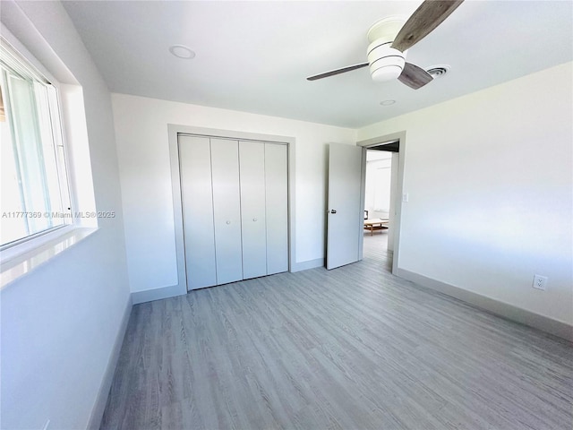 unfurnished bedroom with wood finished floors, visible vents, a ceiling fan, a closet, and baseboards