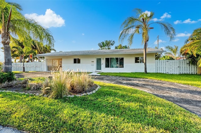 ranch-style house featuring a front yard, driveway, stucco siding, and fence