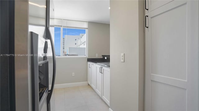 2400 SW 27th Ave Unit 706, Miami, FL 33145 - kitchen with white cabinets, baseboards, light tile patterned flooring, freestanding refrigerator, and dark countertops