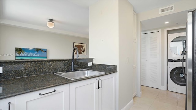 2400 SW 27th Ave Unit 706, Miami, FL 33145 - kitchen featuring stacked washer / dryer, a sink, white cabinetry, light tile patterned floors, and dark stone counters