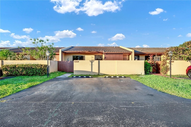 14723 SW 86th Ln, Miami, FL 33193 - view of front facade featuring a fenced front yard, a tiled roof, stucco siding, and uncovered parking