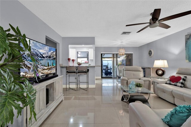 14723 SW 86th Ln, Miami, FL 33193 - living room with a chandelier, a ceiling fan, a textured ceiling, light tile patterned floors, and a fireplace with raised hearth