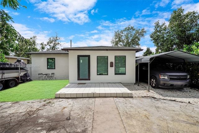 view of front of house with a carport, stucco siding, and a front lawn