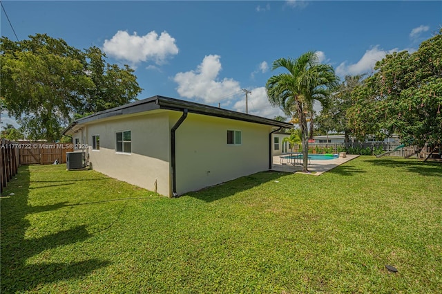 1901 NE 186th Dr, North Miami Beach, FL 33179 - view of property exterior featuring a fenced backyard, stucco siding, a fenced in pool, cooling unit, and a lawn