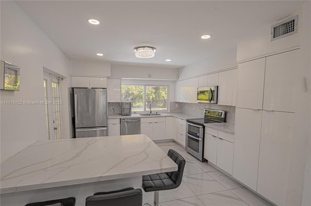 1901 NE 186th Dr, North Miami Beach, FL 33179 - kitchen with visible vents, stainless steel appliances, white cabinets, and modern cabinets