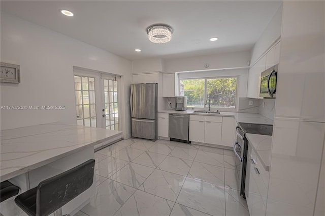1901 NE 186th Dr, North Miami Beach, FL 33179 - kitchen featuring a sink, light stone counters, white cabinets, appliances with stainless steel finishes, and french doors