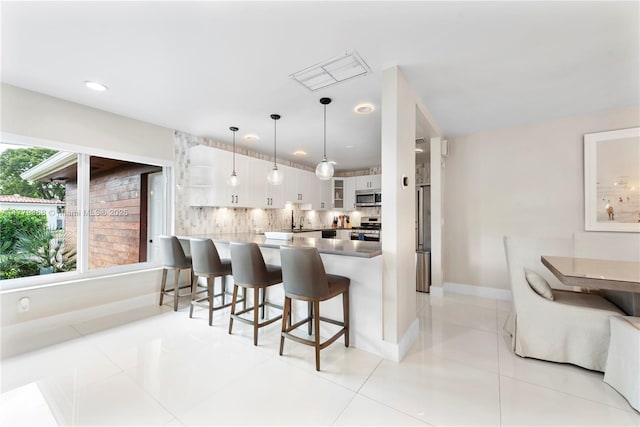 2243 Bayview Ln, North Miami, FL 33181 - kitchen featuring visible vents, a peninsula, glass insert cabinets, a breakfast bar area, and stainless steel appliances