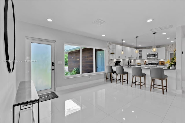 2243 Bayview Ln, North Miami, FL 33181 - kitchen with white cabinets, open shelves, a kitchen breakfast bar, stainless steel appliances, and visible vents