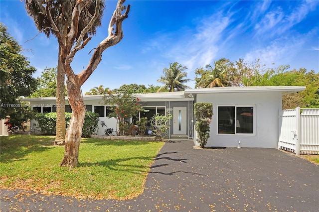 view of front of house featuring stucco siding, fence, and a front lawn