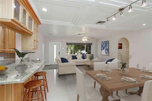 dining space featuring arched walkways, light tile patterned floors, a ceiling fan, and visible vents