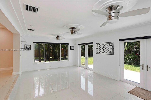 empty room featuring baseboards, light tile patterned floors, visible vents, ceiling fan, and arched walkways
