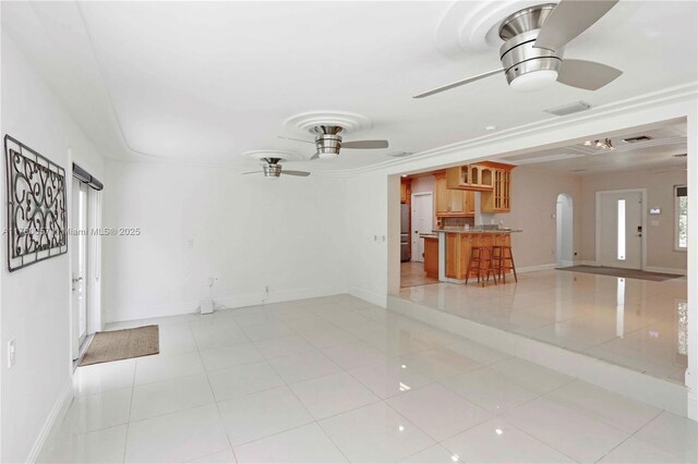spare room featuring ceiling fan, light tile patterned floors, arched walkways, visible vents, and baseboards