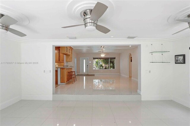 spare room with light tile patterned flooring, arched walkways, ceiling fan, and baseboards