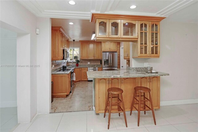 kitchen featuring glass insert cabinets, a kitchen bar, a peninsula, stainless steel appliances, and decorative backsplash