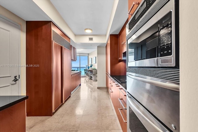 3101 S Ocean Dr Unit 2307, Hollywood, FL 33019 - kitchen with visible vents, light tile patterned floors, built in appliances, dark countertops, and brown cabinetry