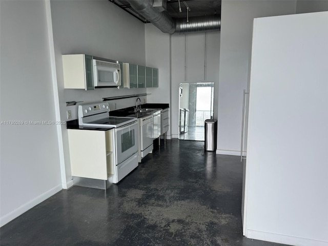 10 SW S River Dr Unit 812, Miami, FL 33130 - kitchen with white appliances, a towering ceiling, finished concrete flooring, white cabinets, and baseboards