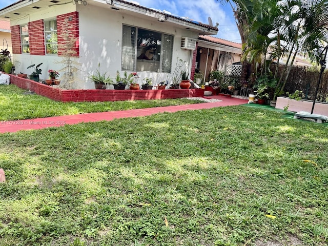 1734 Wiley St, Hollywood, FL 33020 - view of front facade with a front yard, a wall mounted AC, brick siding, and stucco siding