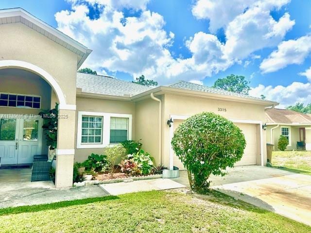 3315 18 W, Lehigh Acres, FL 33971 - view of side of home featuring an attached garage, a shingled roof, driveway, and stucco siding
