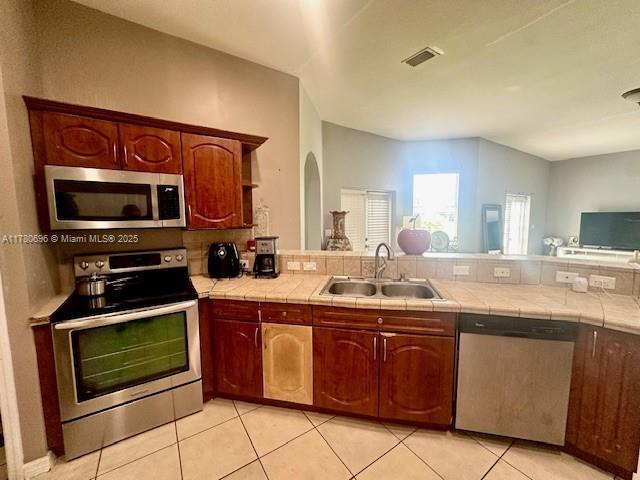 3315 18 W, Lehigh Acres, FL 33971 - kitchen featuring a peninsula, appliances with stainless steel finishes, a sink, open floor plan, and tile counters