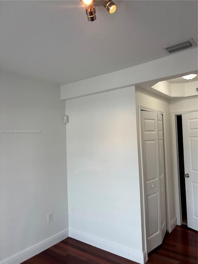 spare room featuring dark wood-type flooring and baseboards