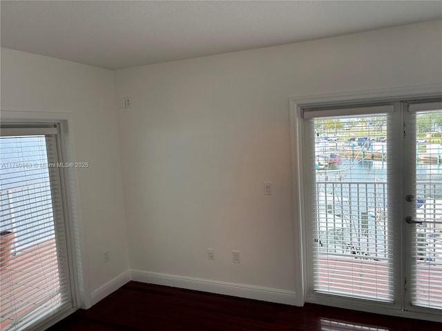 spare room featuring baseboards and dark wood-type flooring