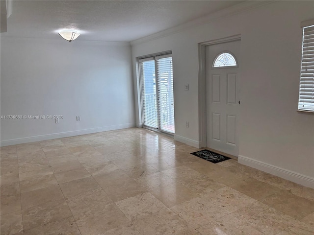 foyer entrance with baseboards and crown molding