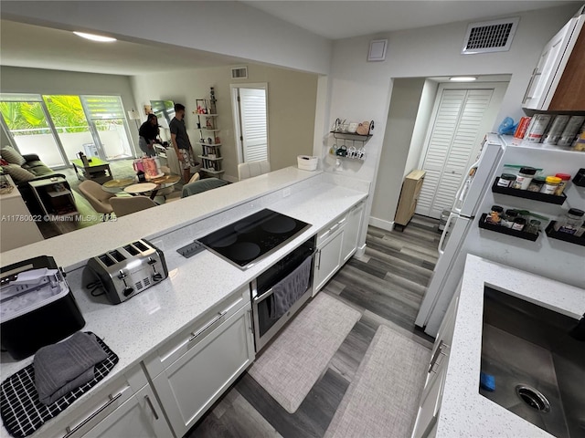 1235 Mariposa Ave Unit 1, Coral Gables, FL 33146 - kitchen featuring dark wood-style floors, oven, visible vents, and black electric cooktop