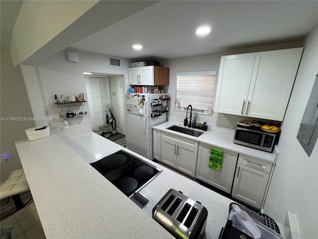 1235 Mariposa Ave Unit 1, Coral Gables, FL 33146 - kitchen featuring a sink, white cabinets, stainless steel microwave, visible vents, and freestanding refrigerator